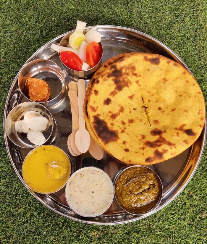 Services A delicious assortment of traditional Indian foods served on a silver plate, showcasing vibrant flavors.
