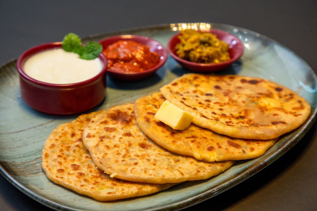 Services Appetizing Indian paratha served with yogurt and pickles on a blue plate.