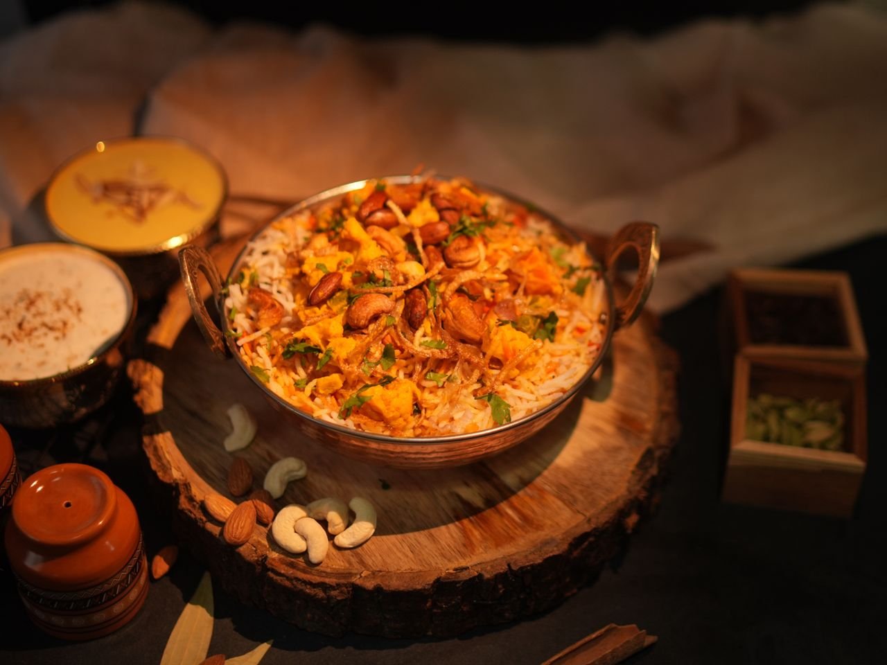 Services A flavorful bowl of authentic Indian biryani garnished with fried onions and cashews, served with sides.